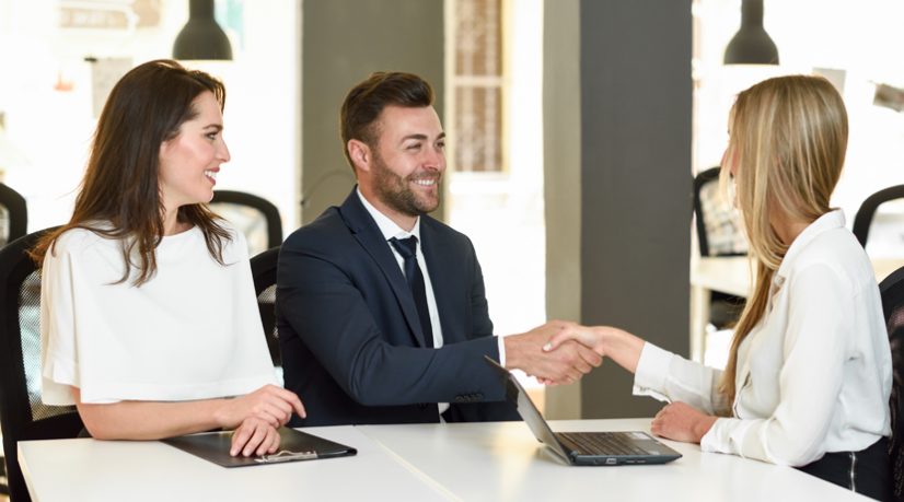Personne assise dans un bureau serrant la main d'une autre femme