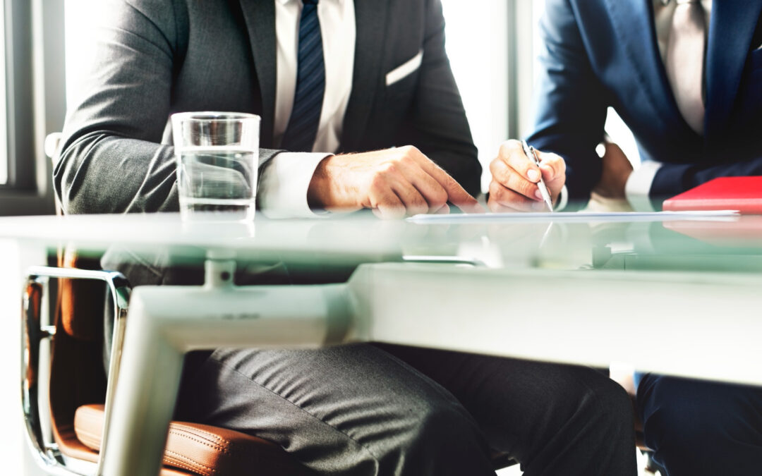 deux hommes en costume lors d'une séance de travail formelle autour d'une table en verre