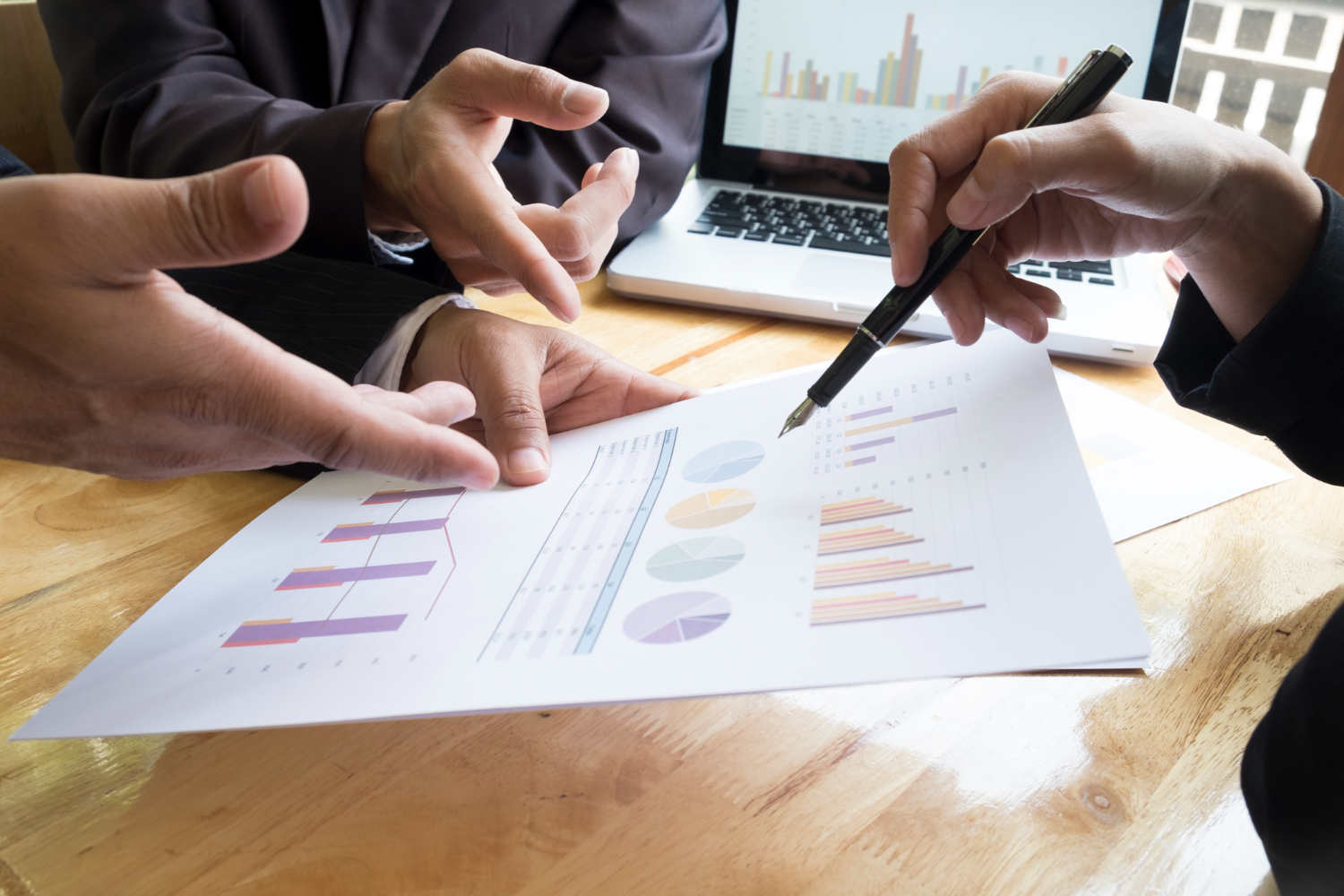 Des professionnels analysent ensemble des graphiques et des documents financiers autour d’une table.