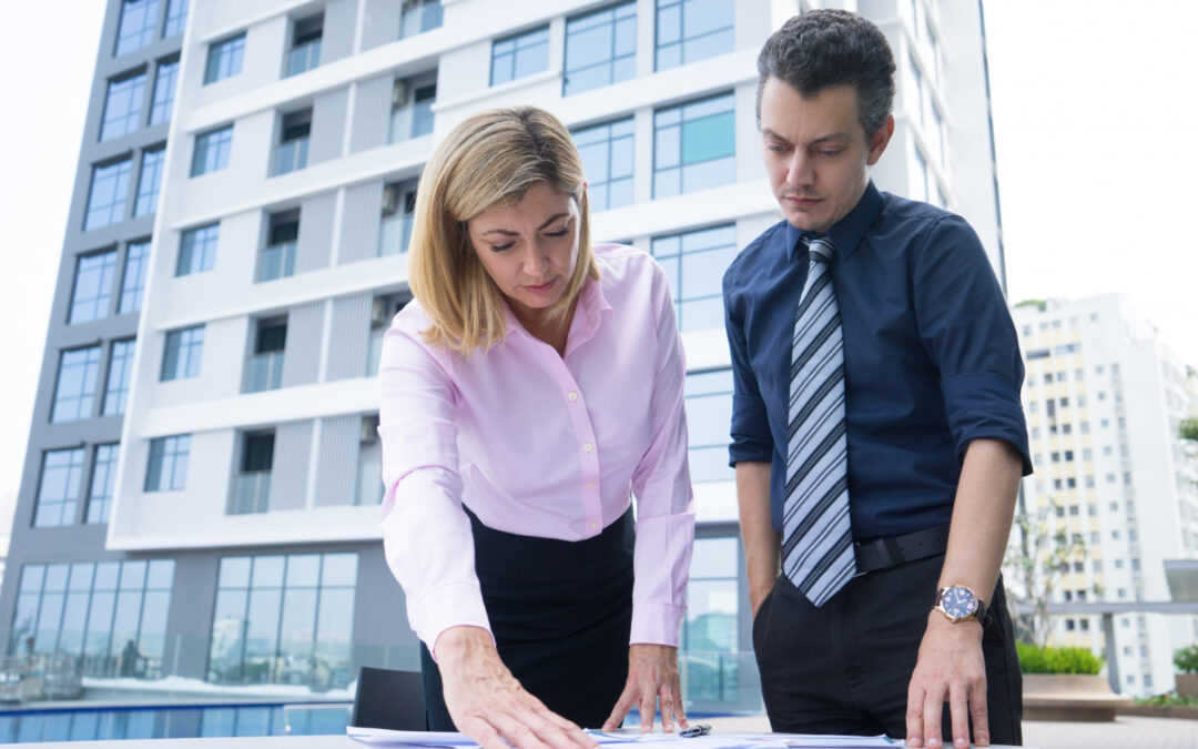 Professionnels analysant des plans devant un immeuble résidentiel moderne