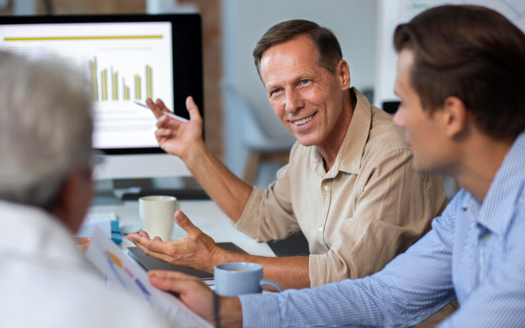 Un consultant senior souriant anime une réunion de travail avec ses collaborateurs